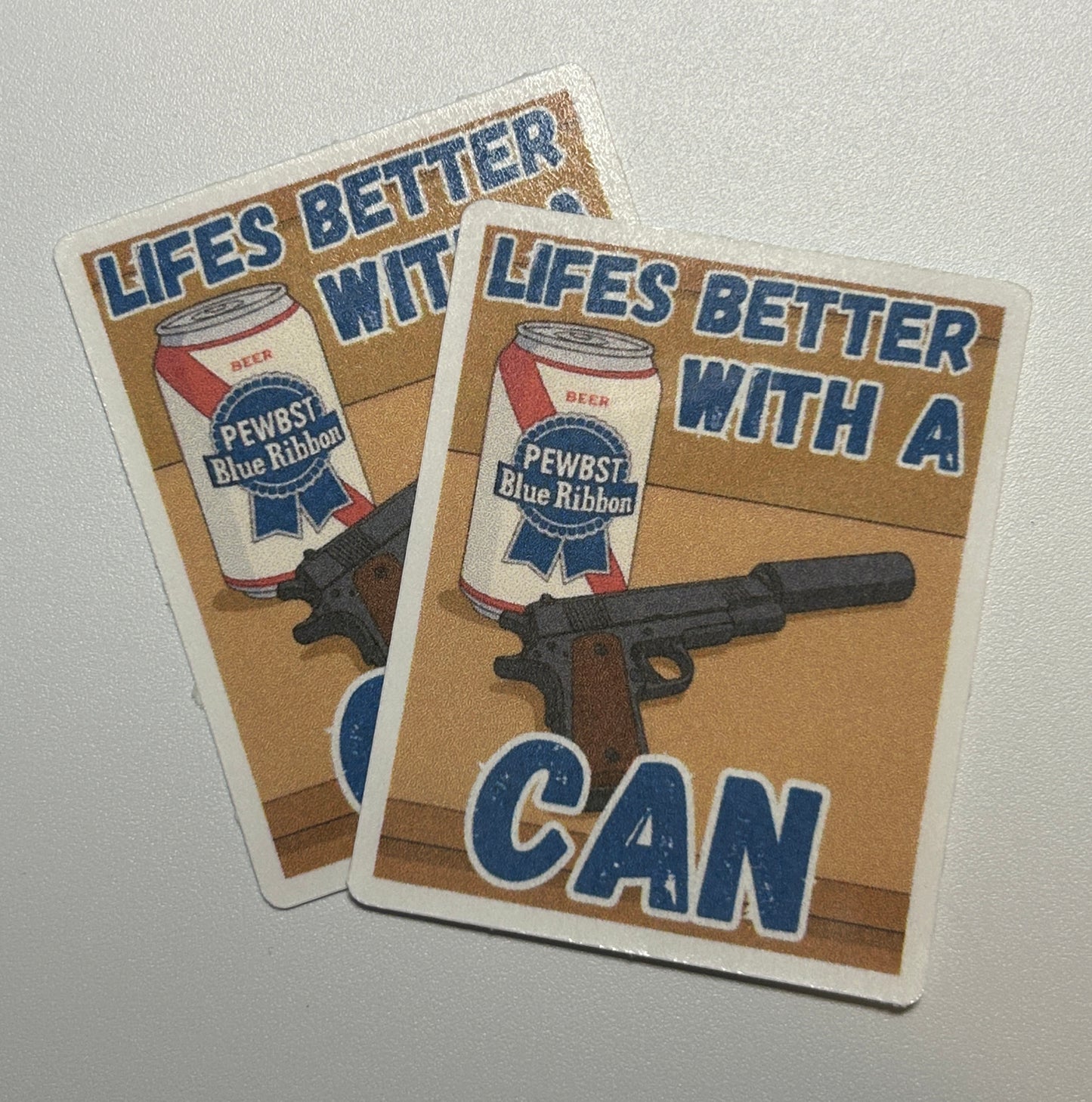 2 Square stickers showing an illustrated beverage can and a handgun graphic with bold text on a tan background.