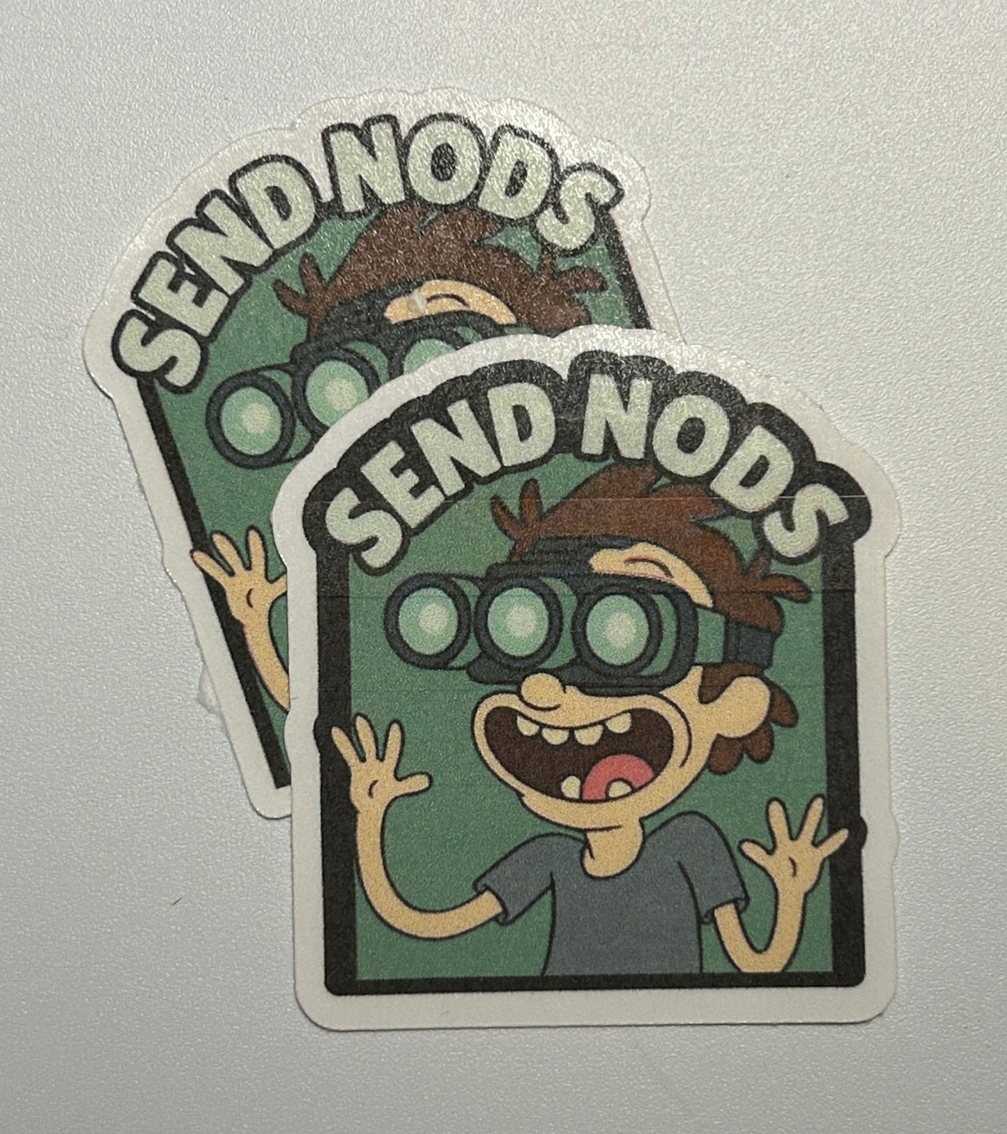 2 Stickers featuring a cartoon character wearing goggles with raised hands and bold text above the illustration.