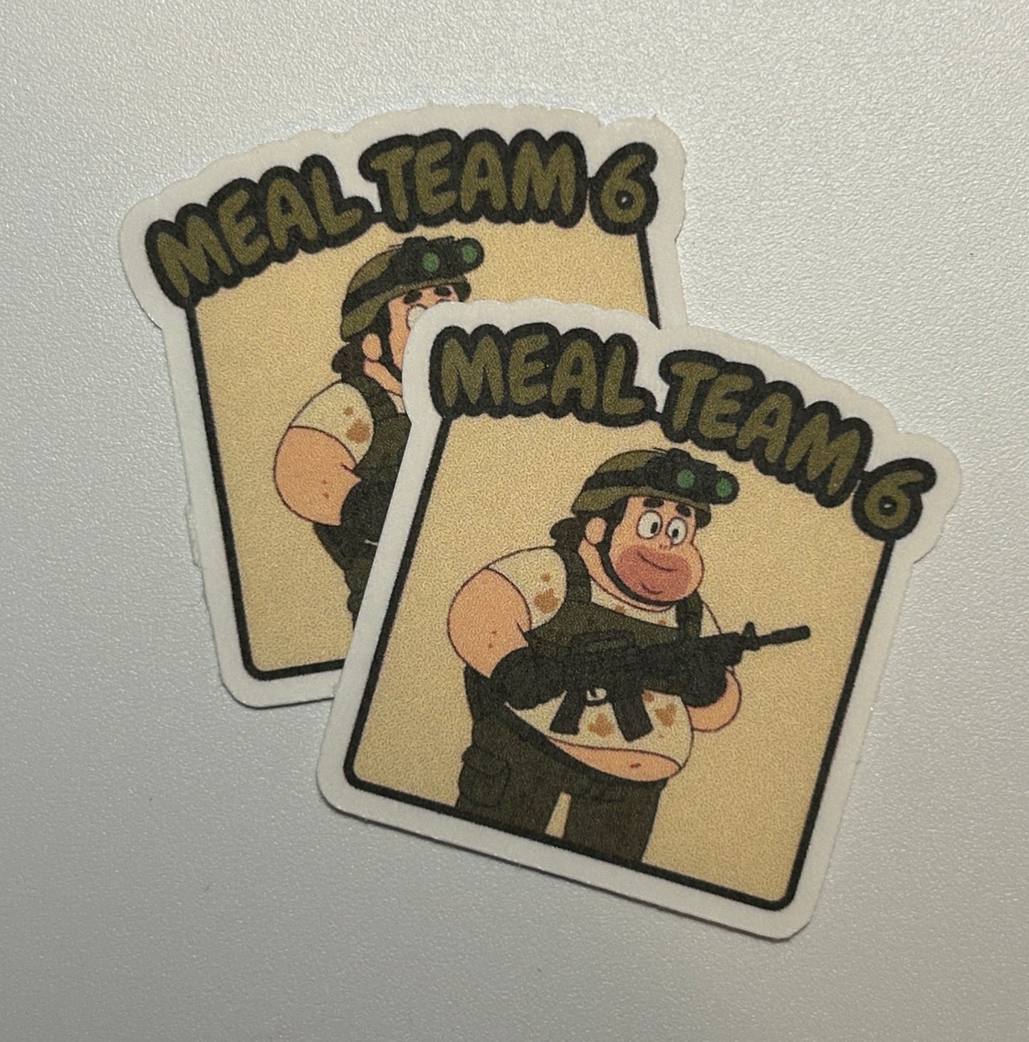 2 Stickers featuring a cartoon-style character holding a rifle, shown against a solid background with text above the illustration.