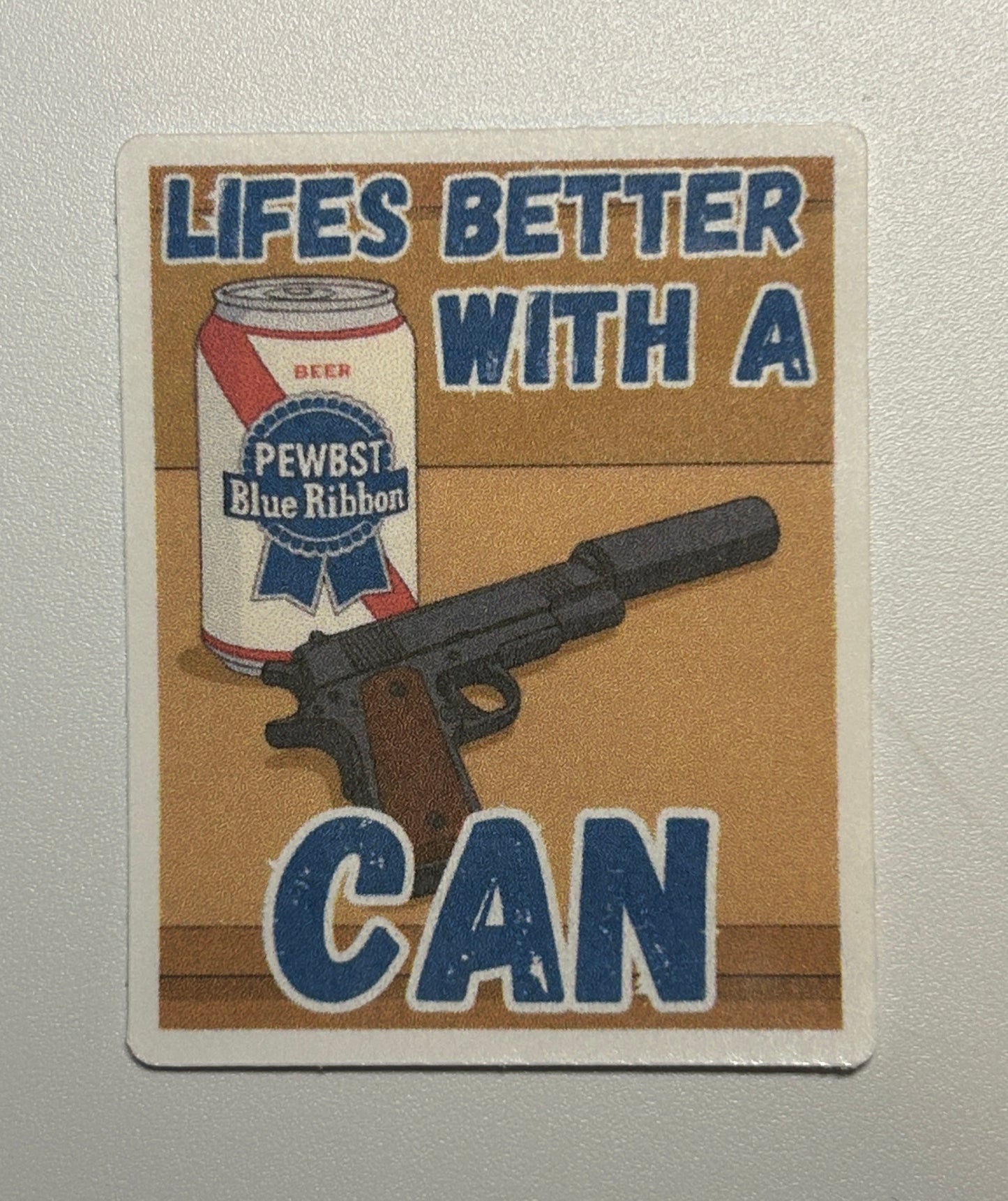 Square sticker showing an illustrated beverage can and a handgun graphic with bold text on a tan background.